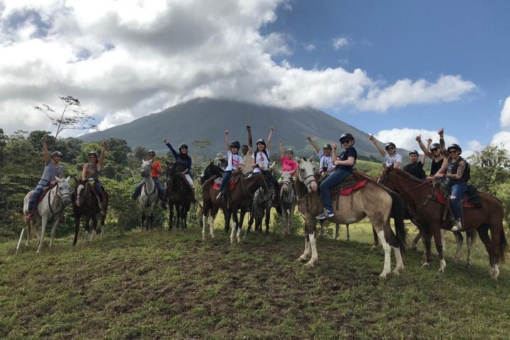 a group of people riding on the back of a horse in a field