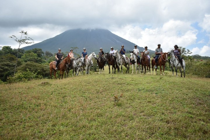 a group of people riding on the back of a horse in a field